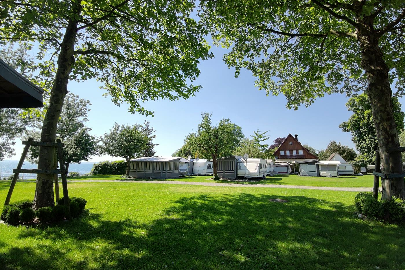 Blick über die Liegewiese des Campingplatzes Nonnenhorn auf Wohnwagen und den Bodensee